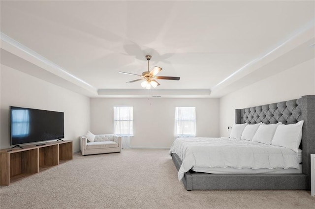 bedroom with a raised ceiling, light colored carpet, ceiling fan, and baseboards