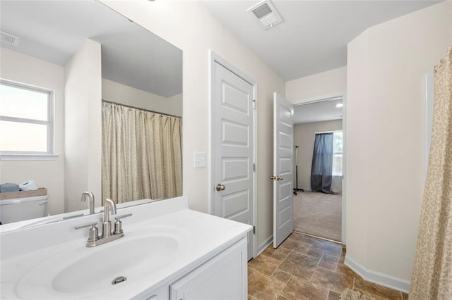 bathroom featuring a healthy amount of sunlight, visible vents, vanity, and baseboards