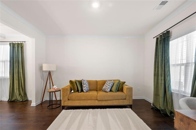 living room featuring ornamental molding, visible vents, baseboards, and wood finished floors