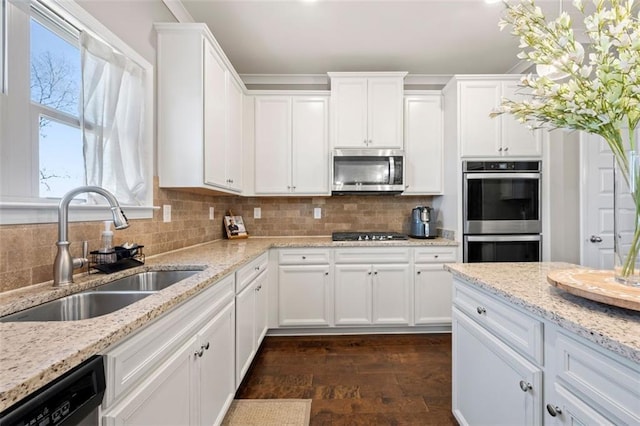 kitchen featuring stainless steel appliances, a sink, white cabinets, and decorative backsplash