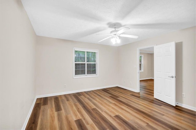 spare room with a ceiling fan, baseboards, wood finished floors, and a textured ceiling
