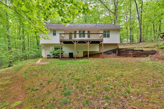 rear view of property with a lawn, a wooden deck, and central AC unit