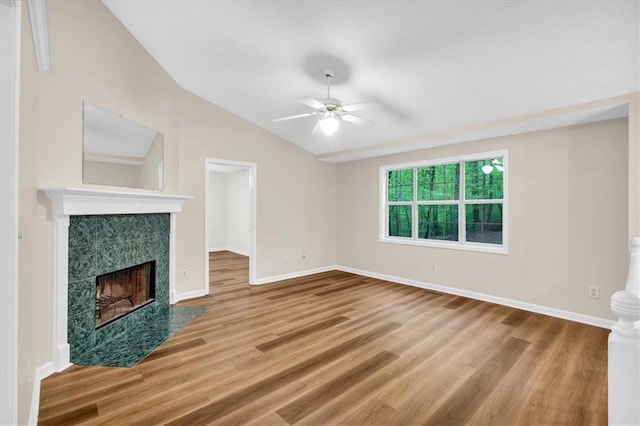 unfurnished living room with a ceiling fan, baseboards, wood finished floors, and a tile fireplace