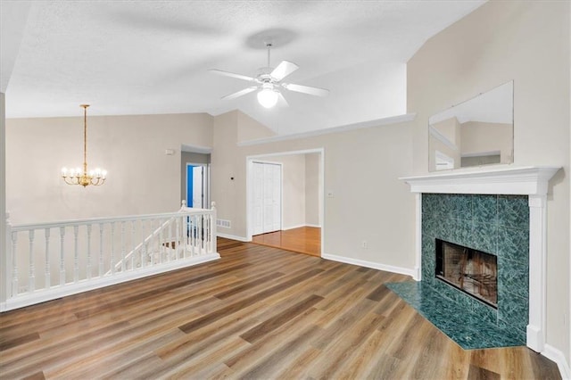 unfurnished living room with baseboards, ceiling fan with notable chandelier, wood finished floors, and lofted ceiling