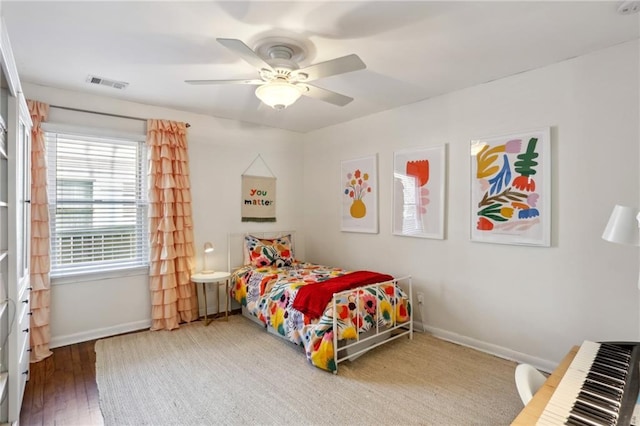 bedroom featuring a ceiling fan, wood finished floors, baseboards, and visible vents