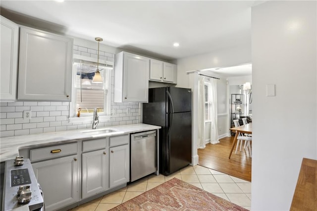 kitchen featuring light tile patterned floors, a healthy amount of sunlight, freestanding refrigerator, and stainless steel dishwasher