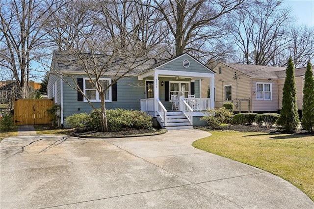 view of front of home with a porch, a gate, and a front lawn