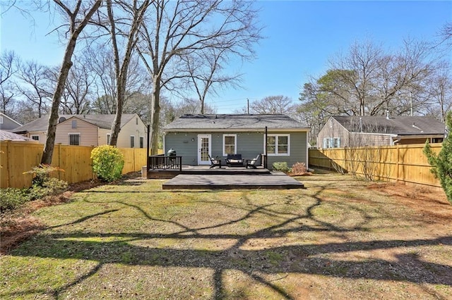 rear view of house with a wooden deck, a yard, and a fenced backyard