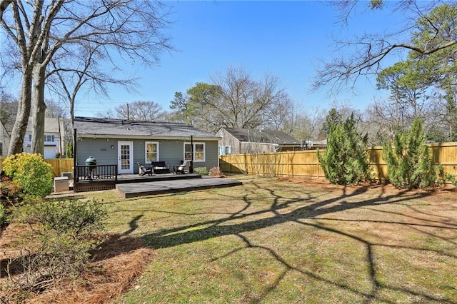 rear view of property with a fenced backyard, a lawn, and a wooden deck