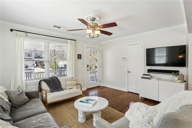 living room with crown molding, wood finished floors, visible vents, and baseboards