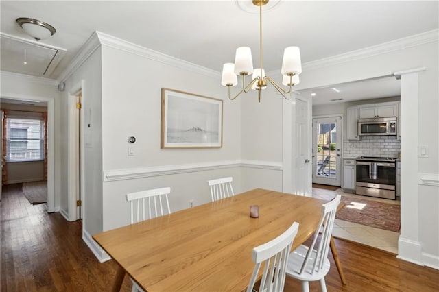 dining area featuring plenty of natural light, ornamental molding, attic access, and wood finished floors