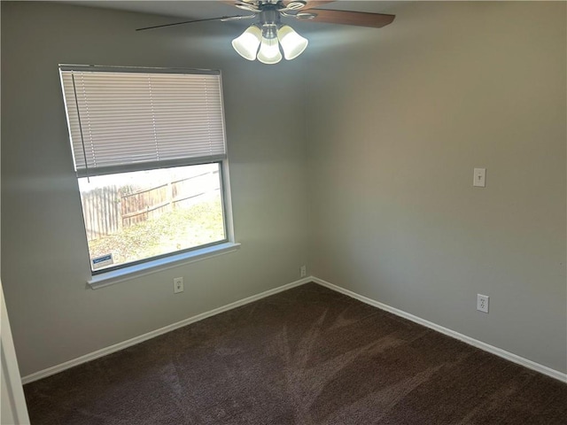 empty room featuring dark carpet, a ceiling fan, and baseboards