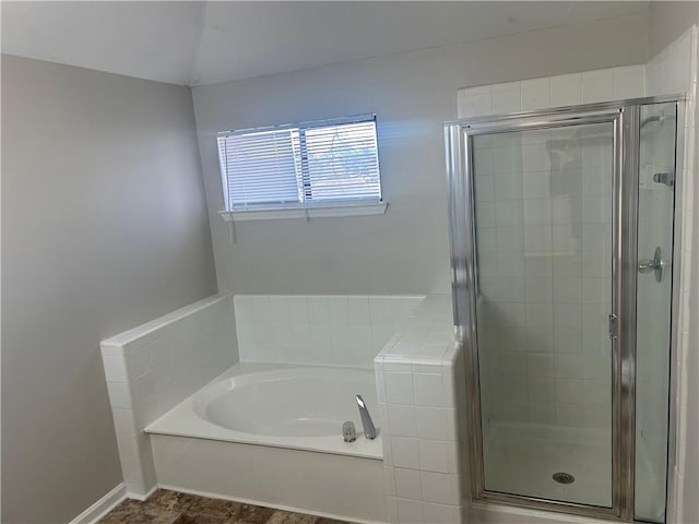 bathroom with a bath, baseboards, and a stall shower