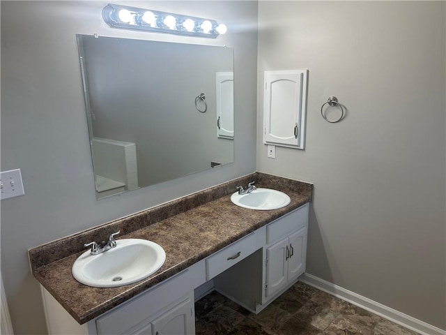 bathroom featuring double vanity, baseboards, and a sink