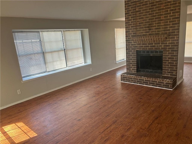 unfurnished living room featuring dark wood finished floors, a fireplace, baseboards, and vaulted ceiling