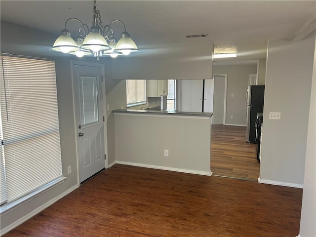 kitchen with visible vents, a chandelier, a peninsula, freestanding refrigerator, and dark wood-style floors