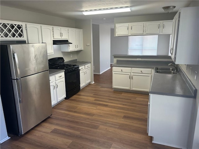 kitchen featuring a sink, dark wood-style floors, white cabinetry, gas stove, and freestanding refrigerator