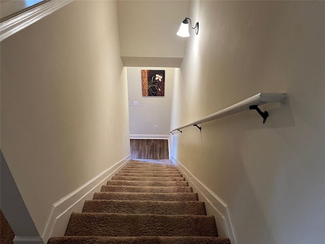 staircase featuring baseboards and wood finished floors