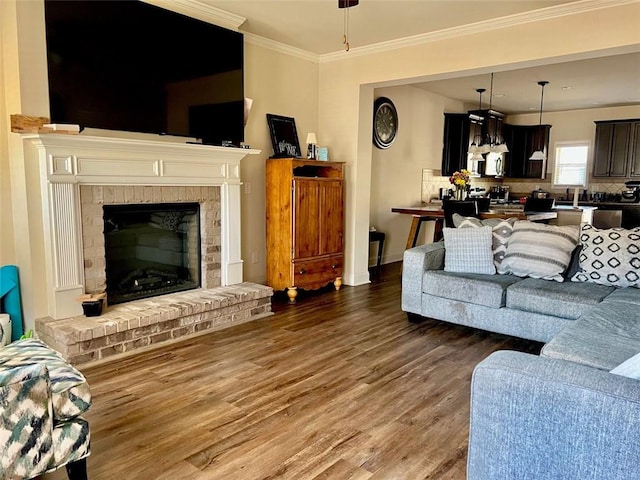 living room with baseboards, a brick fireplace, wood finished floors, and crown molding