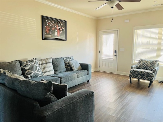 living room featuring baseboards, visible vents, crown molding, and wood finished floors