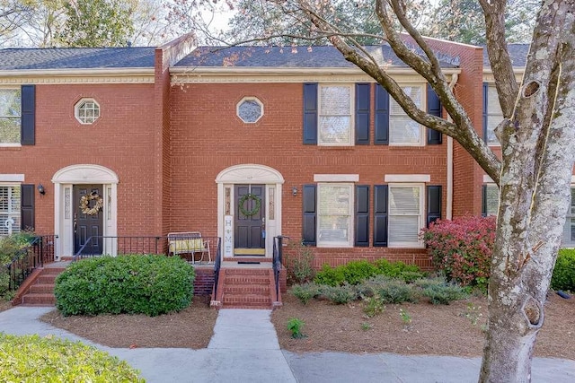 townhome / multi-family property with brick siding and roof with shingles