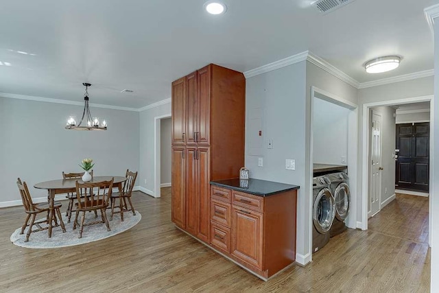kitchen with brown cabinets, dark countertops, light wood-style floors, and washer and clothes dryer
