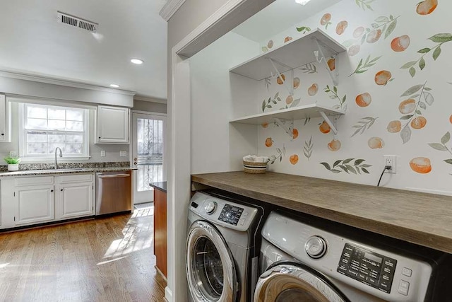 laundry room with crown molding, visible vents, washer and dryer, laundry area, and wood finished floors