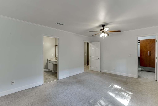 unfurnished bedroom featuring baseboards, visible vents, crown molding, and ensuite bathroom