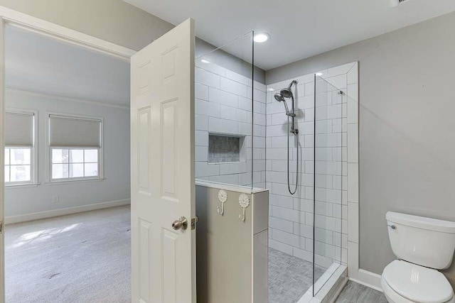 bathroom featuring baseboards, toilet, and a tile shower