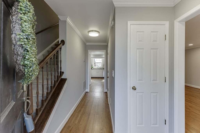 hallway featuring crown molding, stairway, baseboards, visible vents, and wood finished floors