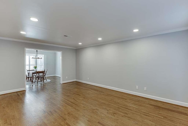 spare room with baseboards, ornamental molding, wood finished floors, recessed lighting, and a notable chandelier