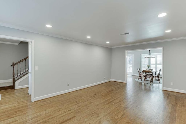 unfurnished room with stairway, a chandelier, light wood finished floors, visible vents, and ornamental molding