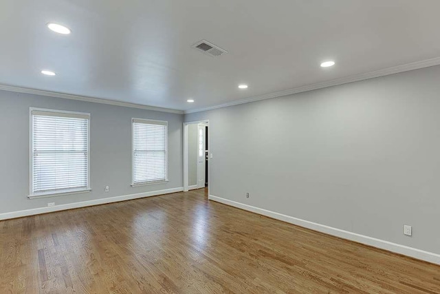 unfurnished room with wood finished floors, ornamental molding, baseboards, and visible vents