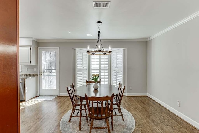 dining space with crown molding, a chandelier, light wood-style flooring, baseboards, and visible vents