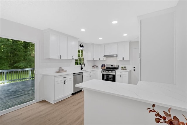5689 Woodland Dr, Acworth, GA 30102 - kitchen featuring appliances with stainless steel finishes, a sink, light wood-style flooring, a peninsula, and white cabinetry