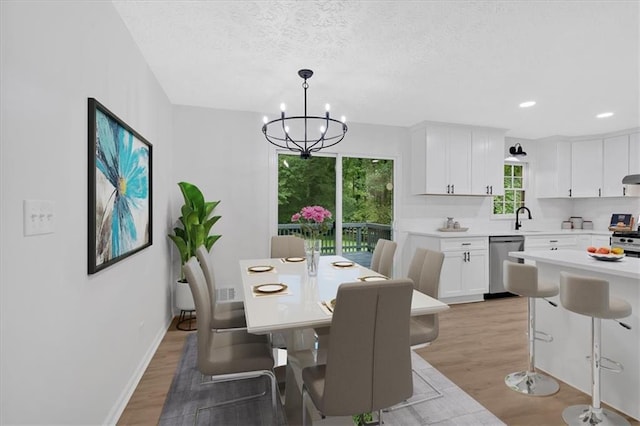 5689 Woodland Dr, Acworth, GA 30102 - dining area with light wood-style flooring, a chandelier, recessed lighting, a textured ceiling, and baseboards