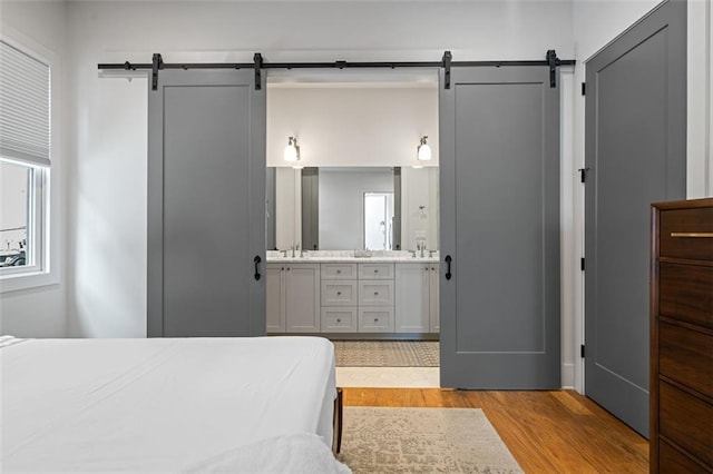 155 Breakspear Ln, Fayetteville, GA 30214 - bedroom with a barn door, light wood-style flooring, connected bathroom, and a sink