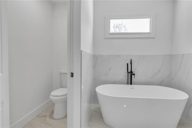 2601 Garland Way, Duluth, GA 30096 - bathroom with marble finish floors, toilet, a soaking tub, a wainscoted wall, and tile walls