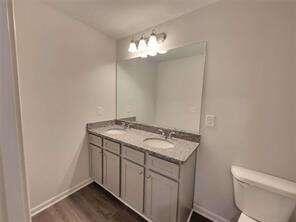 115 Deer Xing, Temple, GA 30179 - bathroom with baseboards, toilet, double vanity, and wood finished floors