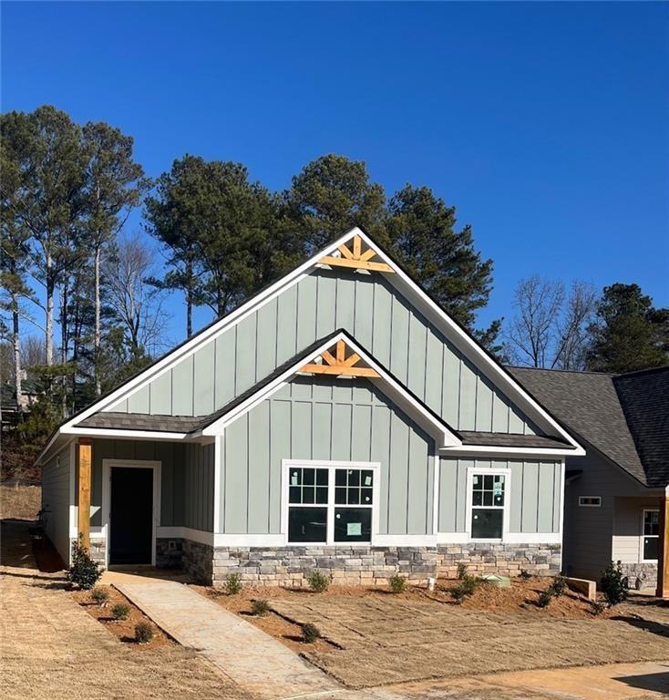 exterior space featuring stone siding, board and batten siding, and roof with shingles