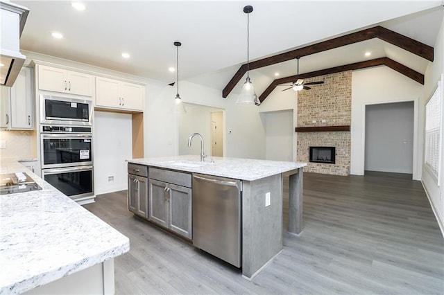 2109 Ella Springs Dr, Covington, GA 30014 - kitchen with appliances with stainless steel finishes, a sink, a ceiling fan, white cabinetry, and light wood-type flooring