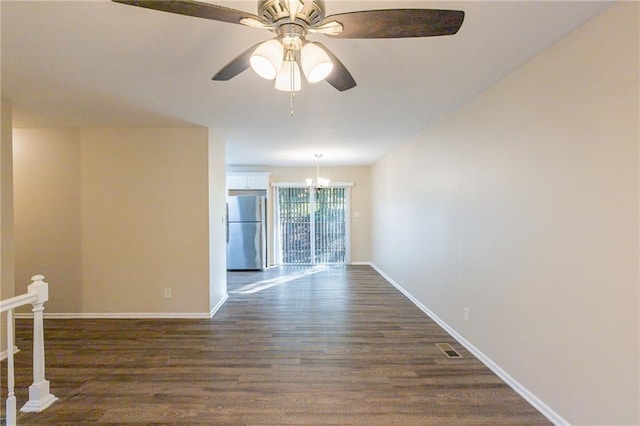 spare room with dark hardwood / wood-style flooring and ceiling fan with notable chandelier