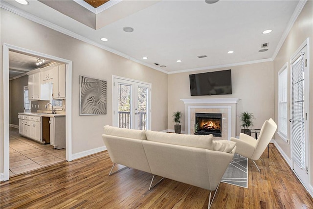 living room featuring sink, light hardwood / wood-style flooring, crown molding, and a fireplace