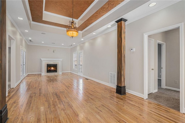 unfurnished living room with ornamental molding, light hardwood / wood-style floors, and a raised ceiling