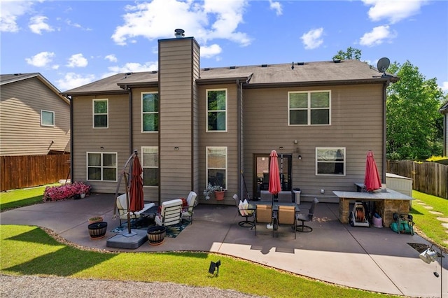 rear view of property featuring a chimney, a fenced backyard, and a patio area