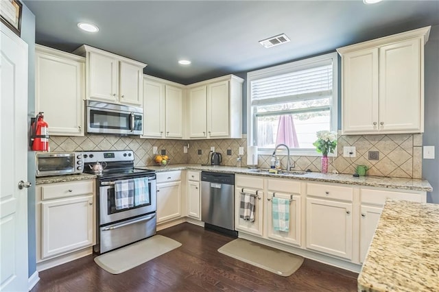 kitchen featuring stainless steel appliances, a sink, dark wood-style flooring, tasteful backsplash, and recessed lighting