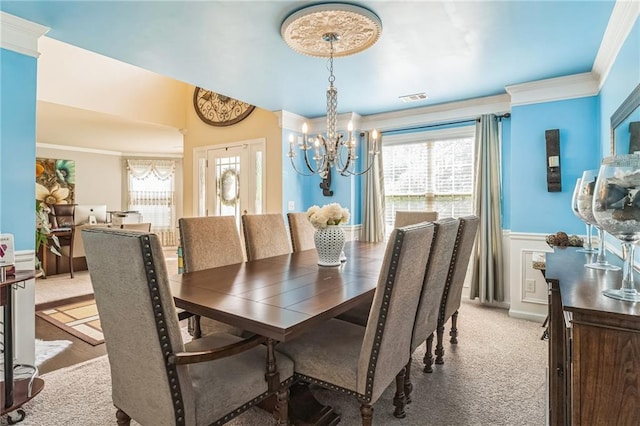 dining area featuring a chandelier, ornamental molding, and wainscoting
