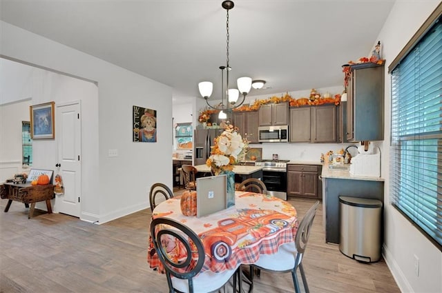 dining space featuring light wood-type flooring, a chandelier, and sink