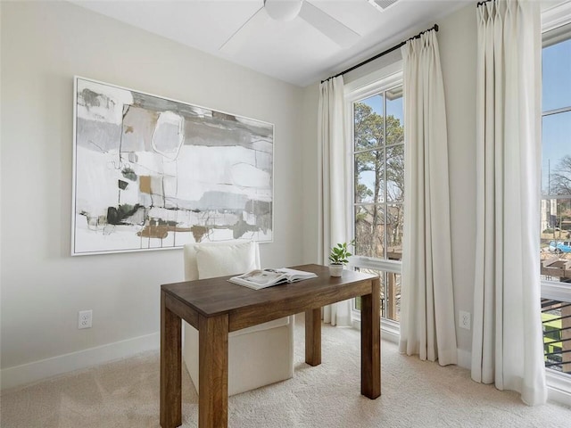 carpeted office space featuring baseboards and a ceiling fan