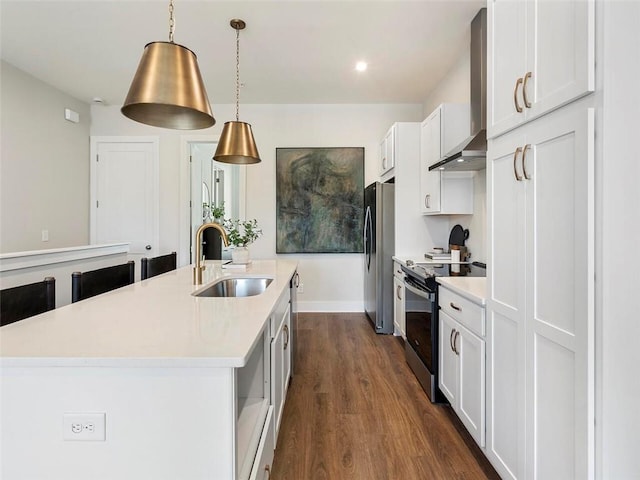 kitchen with electric stove, a center island with sink, freestanding refrigerator, a sink, and wall chimney range hood